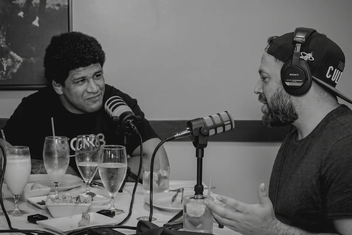 A guest and the host talk into microphones across a restaurant table during a Clinch Chronicles podcast taping